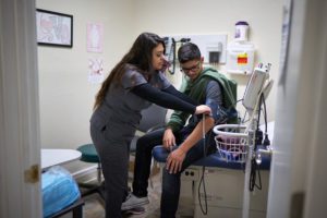 Nurse checks young man's blood pressure